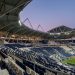 Vue éditoriale réaliste du stade Matmut Atlantique presque vide au crépuscule, avec des tribunes bleu marine et blanches sans logos.