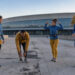 Quatre coureurs, deux femmes et deux hommes, s’échauffent devant un vélodrome à Marseille au petit matin, dans une douce lumière automnale.