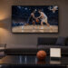 Salon moderne éclairé la nuit, avec un écran montrant un match de basketball, un ballon orange et un calendrier minimaliste posé près d’une table basse.